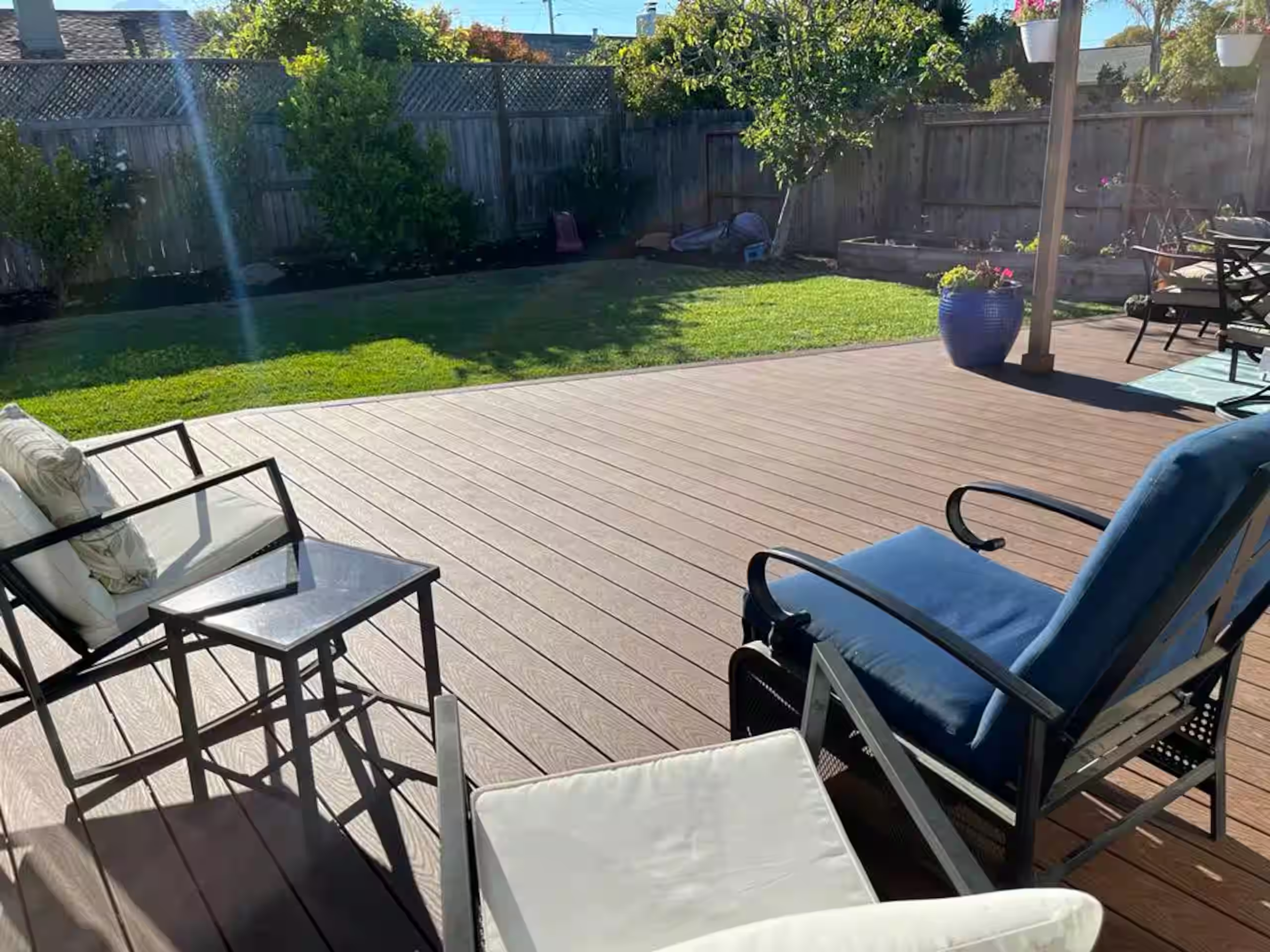 Backyard deck seating area with a view of the fenced lawn and garden