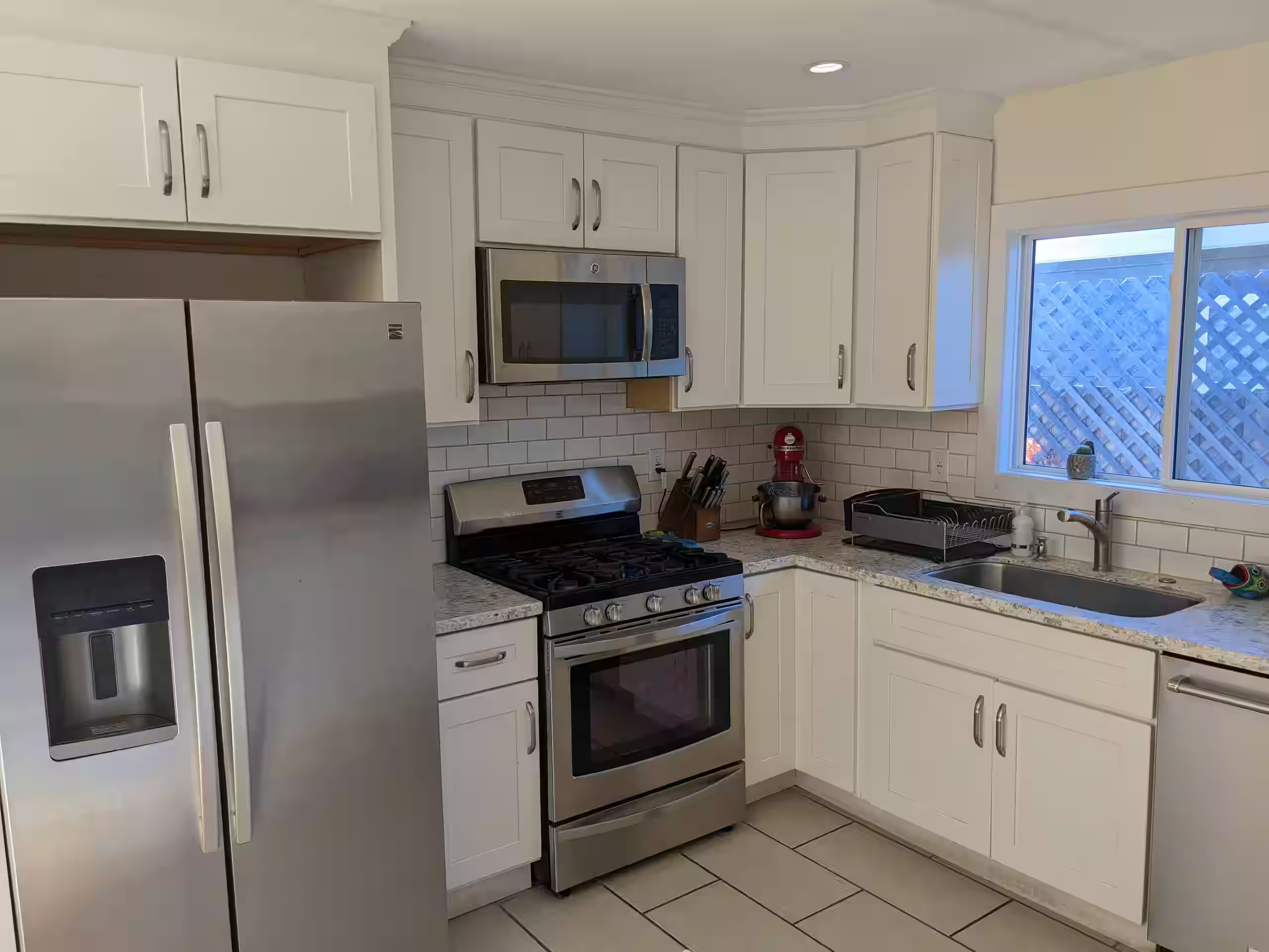 Kitchen with stainless steel refrigerator, gas range, and white shaker cabinets